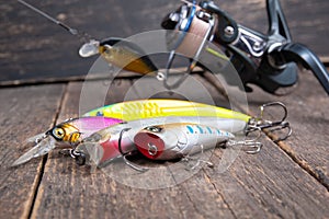 Fishing spinning reel and fishing lures on wooden table