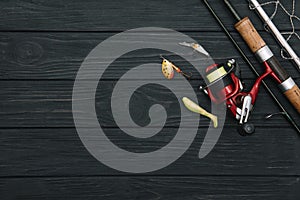 Fishing tackle - fishing spinning, hooks and lures on darken wooden background. Top view