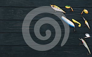 Fishing tackle - fishing spinning, hooks and lures on darken wooden background. Top view