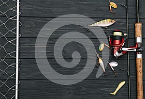 Fishing tackle - fishing spinning, hooks and lures on darken wooden background. Top view