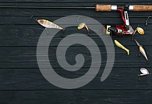 Fishing tackle - fishing spinning, hooks and lures on darken wooden background. Top view