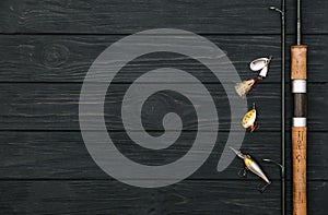 Fishing tackle - fishing spinning, hooks and lures on darken wooden background. Top view