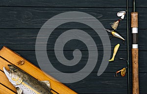 Fishing tackle - fishing spinning, hooks and lures on darken wooden background. Top view