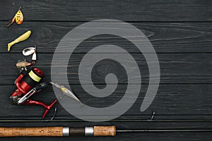 Fishing tackle - fishing spinning, hooks and lures on darken wooden background. Top view