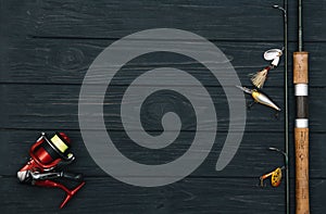 Fishing tackle - fishing spinning, hooks and lures on darken wooden background. Top view