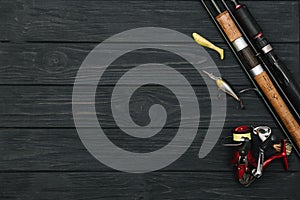 Fishing tackle - fishing spinning, hooks and lures on darken wooden background. Top view