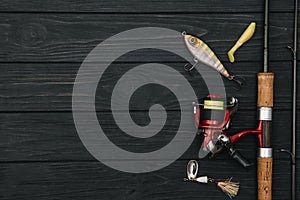 Fishing tackle - fishing spinning, hooks and lures on darken wooden background. Top view