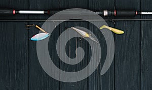 Fishing tackle - fishing spinning, hooks and lures on darken wooden background. Top view