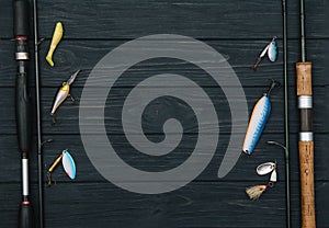 Fishing tackle - fishing spinning, hooks and lures on darken wooden background. Top view