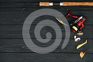 Fishing tackle - fishing spinning, hooks and lures on darken wooden background. Top view