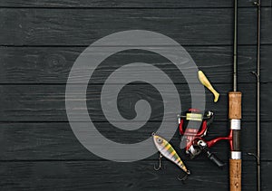 Fishing tackle - fishing spinning, hooks and lures on darken wooden background. Top view