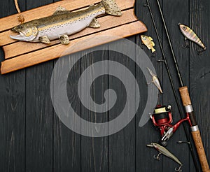 Fishing tackle - fishing spinning, hooks and lures on darken wooden background. Top view