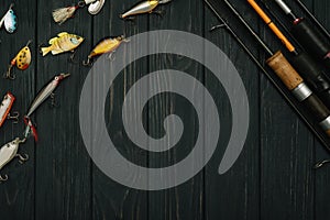 Fishing tackle - fishing spinning, hooks and lures on darken wooden background. Top view