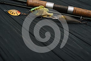 Fishing tackle - fishing spinning, hooks and lures on darken wooden background. Top view