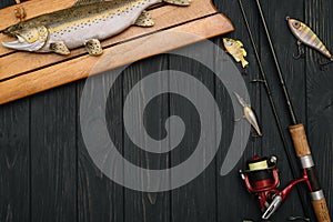 Fishing tackle - fishing spinning, hooks and lures on darken wooden background. Top view