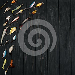 Fishing tackle - fishing spinning, hooks and lures on darken wooden background. Top view