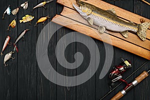 Fishing tackle - fishing spinning, hooks and lures on darken wooden background. Top view