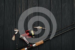 Fishing tackle - fishing spinning, hooks and lures on darken wooden background. Top view