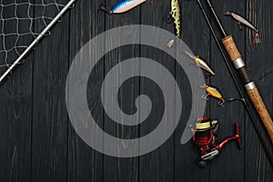 Fishing tackle - fishing spinning, hooks and lures on darken wooden background. Top view