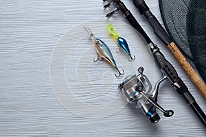 Fishing tackle - fishing spinning, hooks and lures on wooden background.