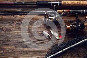 Fishing tackle - fishing spinning, hooks and lures on wooden background.