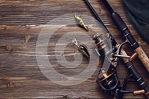 Fishing tackle - fishing spinning, hooks and lures on wooden background.