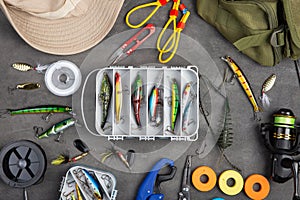 Fishing tackle - fishing spinning rod, hooks and lures on gray background. Active hobby recreation concept