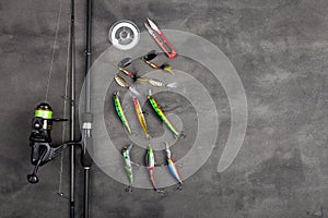 Fishing tackle - fishing spinning rod, hooks and lures on gray background. Active hobby recreation concept