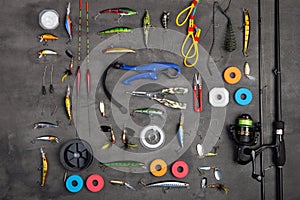 Fishing tackle - fishing spinning rod, hooks and lures on gray background. Active hobby recreation concept