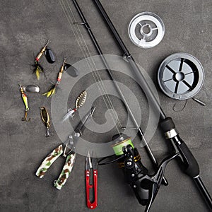 Fishing tackle - fishing spinning rod, hooks and lures on gray background. Active hobby recreation concept