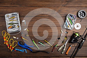 Fishing tackle - fishing spinning rod, hooks and lures on wooden background. Active hobby recreation concept