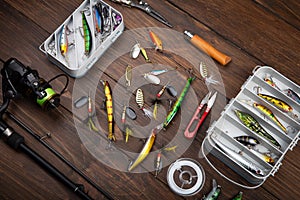 Fishing tackle - fishing spinning rod, hooks and lures on wooden background. Active hobby recreation concept