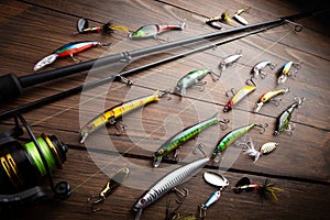 Fishing tackle - fishing spinning rod, hooks and lures on wooden background. Active hobby recreation concept