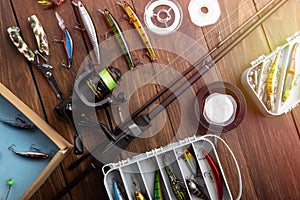 Fishing tackle - fishing spinning rod, hooks and lures on wooden background. Active hobby recreation concept