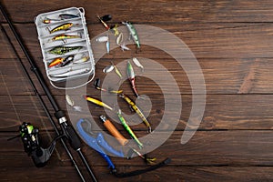 Fishing tackle - fishing spinning rod, hooks and lures on wooden background. Active hobby recreation concept