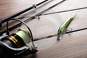 Fishing tackle - fishing spinning rod, hooks and lures on wooden background. Active hobby recreation concept