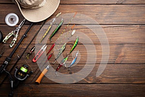 Fishing tackle - fishing spinning rod, hooks and lures on wooden background. Active hobby recreation concept