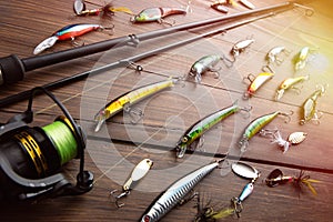 Fishing tackle - fishing spinning rod, hooks and lures on wooden background. Active hobby recreation concept