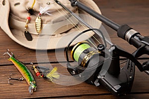 Fishing tackle - fishing spinning rod, hooks and lures on wooden background. Active hobby recreation concept