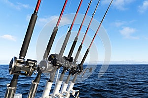 Fishing trolling boat rods in rod holder. Big game fishing. Fishing reels and rods pattern on boat. Sea fishing rods and reels in
