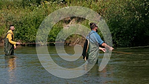 Fishing, two men fishing on the river, standing in the water, a small current