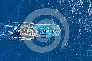 Fishing vessel boat floating in the blue sea, aerial view from above