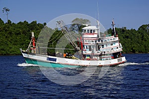 Fishing vessel underway at sea over blue sky and sea