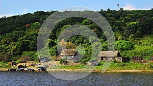 Fishing village on bank of river in green forest. Old wooden