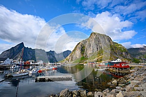 A fishing village at Hamnoy Reine, Norway during the daytime. The blue skies and mountains reflect the water