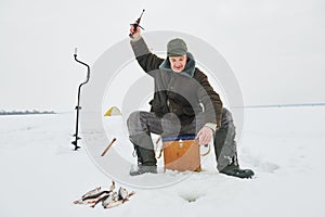 Fishing at winter. Fisherman hooking fish on ice