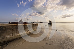 Fishing wooden boat moored on the beach at sunset