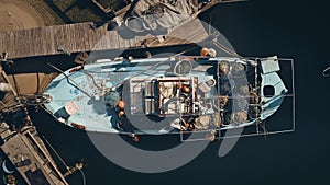 Fishing wooden boat on the pier. Aerial closeup view. Boat bottom full of fishing equipment, nets