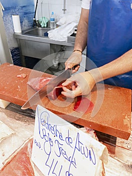 A fishmonger cutting a piece of Red Tuna in a Spanish market. Cadiz, Andalusia, Spain