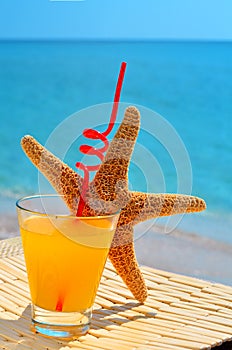 Fishstar, glass of orange cocktail against the sea photo